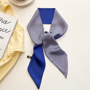 Détail d'un foulard étroit en soie à carreaux bleu et blanc sur un fond de bureau