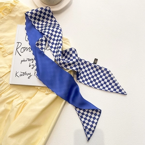 Détail du foulard en soie à damier bleu et blanc sur vêtement jaune et livre