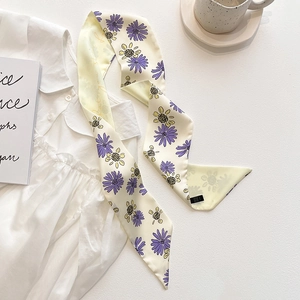 Détail d'un foulard en soie avec marguerites jaunes et lettrage sur une chemise blanche