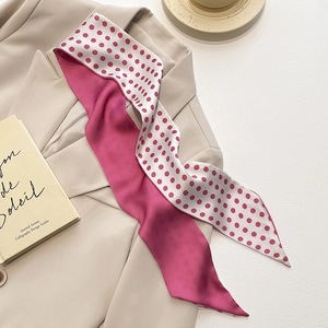 Detail van een smalle roze zijden sjaal met stippen op een beige blazer kraag
