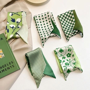Close-up of five green silk scarves with polka dots and floral patterns for handbags