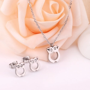Détail de parure bijoux chouette avec strass sur fond de rose rose