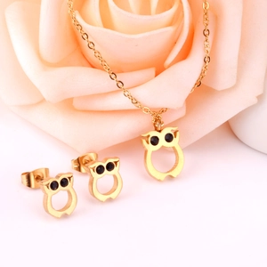 Détails d'une parure bijoux hibou dorée avec collier et boucles sur fond de rose rose