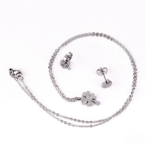 Dettaglio di set gioielli quadrifoglio argento con finitura satinata su orecchini e collana