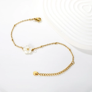 Elegant gold stainless steel bracelet with white shell flower charm on white background
