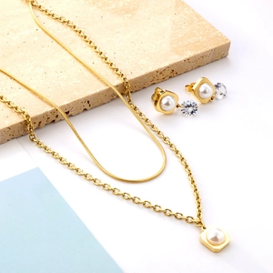 Detail of gold double-layer pearl necklace and earrings set on stone display