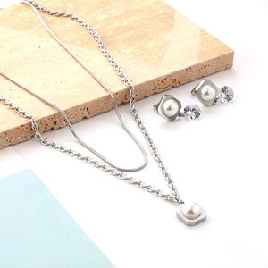 Detail of silver double-layer necklace and pearl earrings set on a stone prop