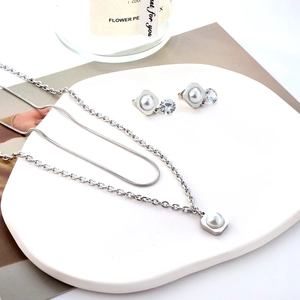 Detail of silver jewelry set with pearls and crystals on geometric layered necklace and studs