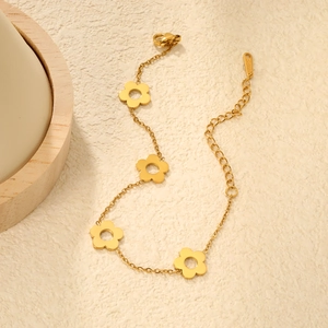 Bracelet en acier inoxydable doré avec de délicats charms évidés en forme de fleurs