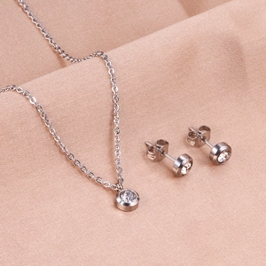 Vue détaillée de parure de bijoux en acier argenté avec collier et boucles d'oreilles cristal