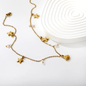 Golden starfish and seashell necklace with white pearls on elegant white background