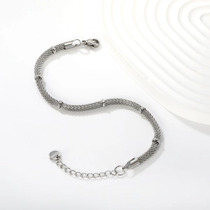 Detailed macro of silver stainless steel woven mesh bracelet with small beads and lobster clasp