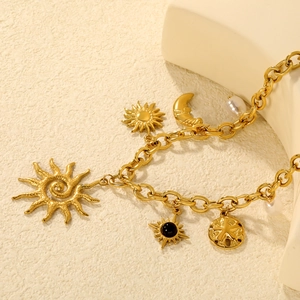 Gold celestial chain necklace with sun moon star charms and baroque pearls on cream background