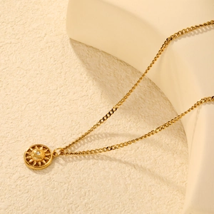 Collana dorata con ciondolo solare e zircone scintillante su sfondo moderno minimalista
