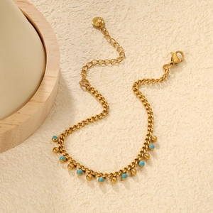 Golden link bracelet with sky blue beads and adjustable lobster clasp on textured background