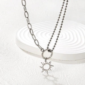 Silberne Doppelkette mit Sonnenanhänger und Perlenkette auf weißem Display