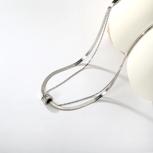 Dettaglio di una collana d'argento a doppio strato con pendente cilindrico con zirconi