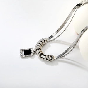 Minimalist double-layer stainless steel necklace with black onyx square pendant on white background