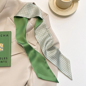 Detail of green silk twilly scarf with star prints on a beige blazer accessory