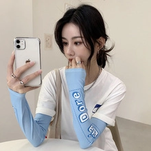 Close-up of light blue sun protection arm sleeves with Lla Dore print and white trim