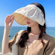 Outdoor close-up of a cream wide-brim sun hat with black text label and natural folds
