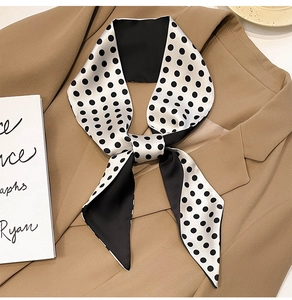 Close-up of a black and white polka dot silk twilly scarf tied on a khaki blazer collar