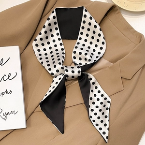 Elegant black and white polka dot silk skinny scarf tied as a bow on a beige blazer collar