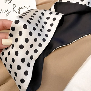 Detail of high-gloss satin silk scarf with black polka dots and solid black reverse