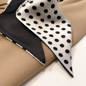 Close-up of elegant silk texture neck scarf with classic black and white polka dot pattern