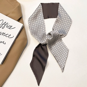 Detail of grey houndstooth silk scarf tied on brown blazer with chic office stationery