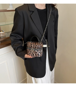 Detail view of leopard print box bag with metal chain strap and leather handle