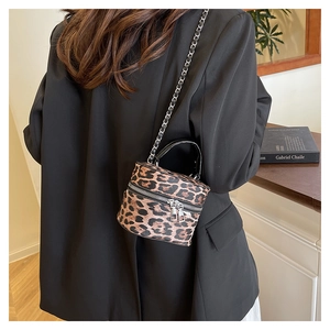 Detailed side view of mini leopard print bucket bag with chain strap on a black blazer