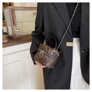 Detail of leopard print bucket bag with leather handle and silver metal chain strap