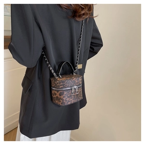 Detailed view of leopard print mini box bag with chain strap on a black blazer