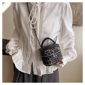 Detailed view of leopard print mini box bag with silver zippers and chain strap