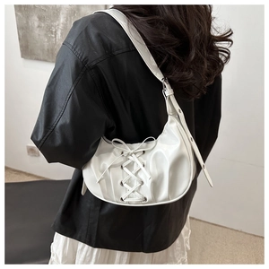 Détail du sac hobo blanc brillant avec design à lacets croisés et décoration de nœud