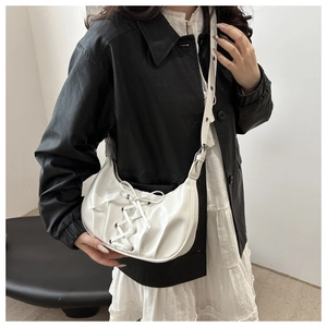 Détail du sac croissant plissé blanc avec lacets croisés et nœud porté par le mannequin