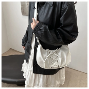 Détail du sac croissant plissé blanc avec rubans à nœuds et œillets métalliques latéraux