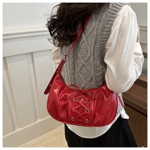 Détail du sac à bandoulière rouge en demi-lune avec laçage et œillets métalliques