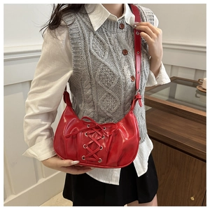 Détail d'un sac bandoulière rouge vif avec laçage et œillets en métal argenté