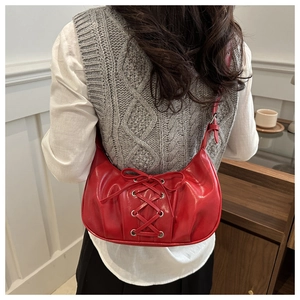 Vue détaillée d'un sac à bandoulière demi-lune rouge avec un design élégant à lacets et anneaux