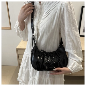 Détail du sac à bandoulière noir style corset avec œillets et lacets croisés