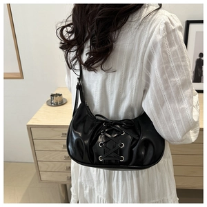 Détail du sac à bandoulière noir en demi-lune avec lacets porté par un mannequin
