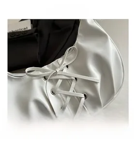Détail du sac demi-lune en cuir PU blanc avec lacets chic et œillets métalliques argentés
