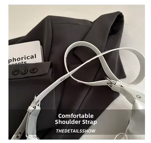Détail de la bandoulière réglable en cuir blanc avec œillets argentés et boucles