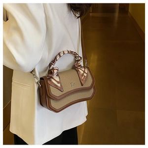 Detail of woven flap bag with silk scarf handle and metal D logo worn by model