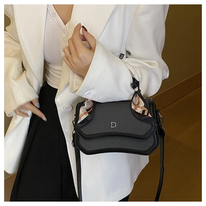 Detail of black leather handbag with twill flap, silver D logo and orange silk scarf