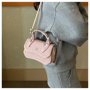 Close-up of pink textured fabric bag with silver D-logo and silk scarf handle detail