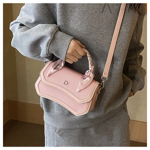 Pink woven handbag detail with silver D-clasp and silk scarf-wrapped handle on a model