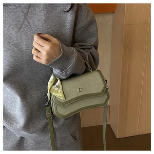 Detail of green corduroy shoulder bag with metal D logo and decorative silk scarf